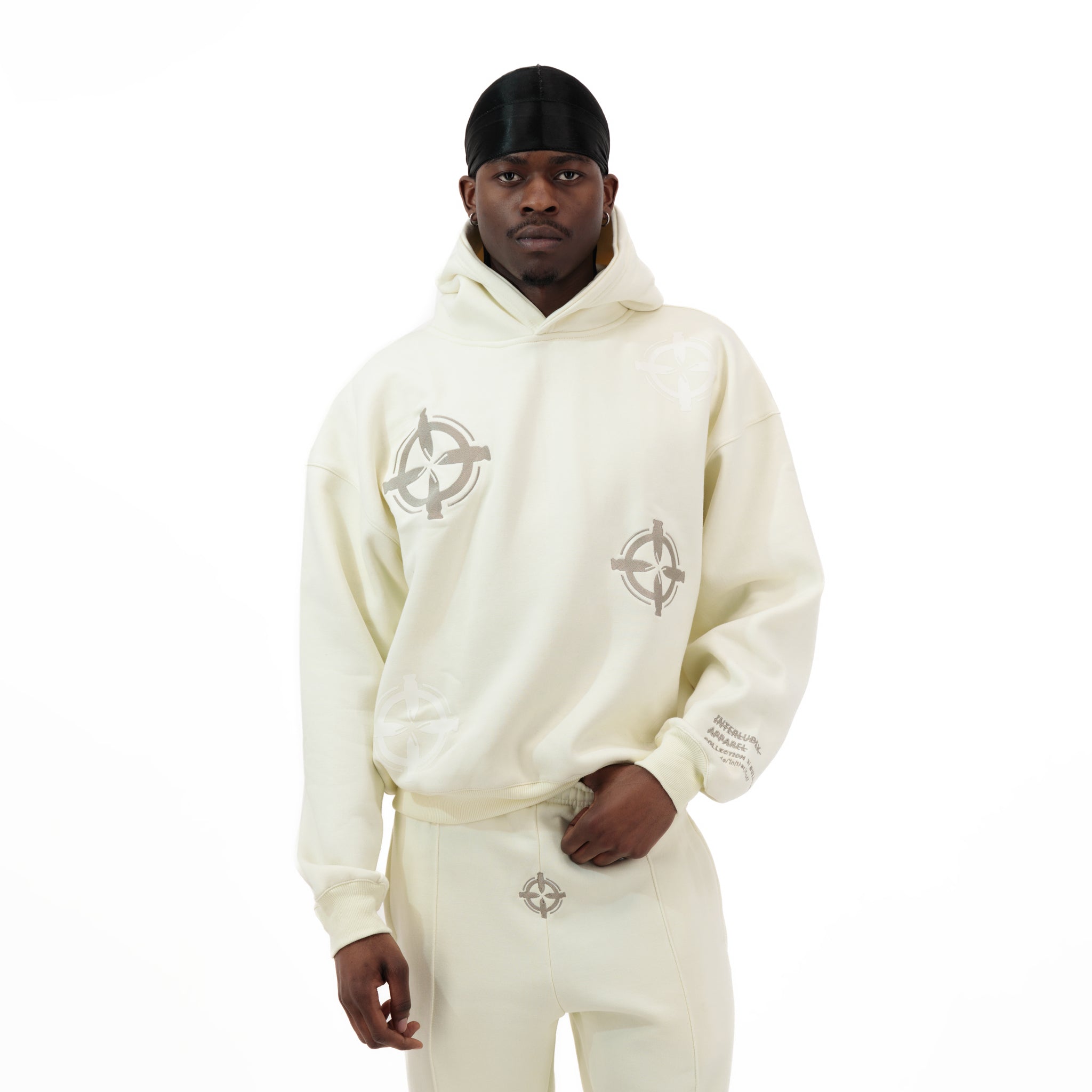 Man wearing cream hoodie and sweatpants with circular logo designs
