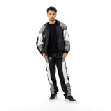 Man wearing a black, grey, and white tracksuit with a black t-shirt and black sneakers