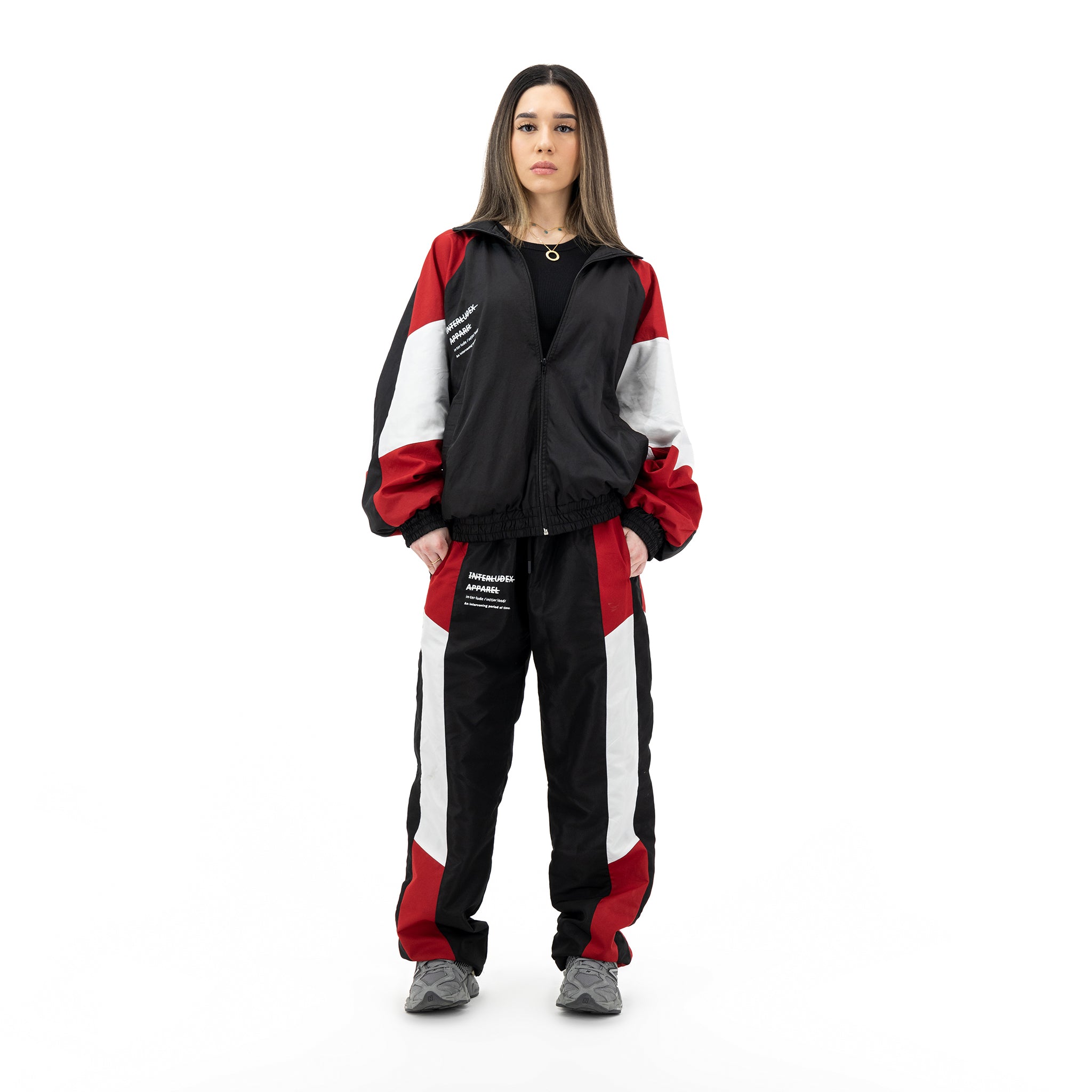 Woman wearing black, red, and white tracksuit with black shirt and gold necklace