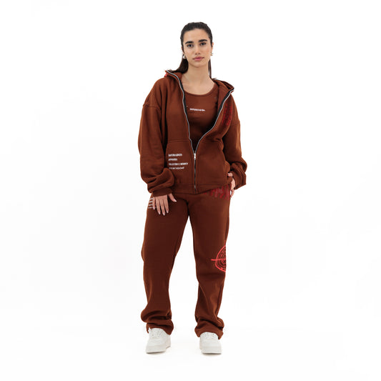 Woman wearing a brown zip-up hoodie, matching sweatpants with red graphic, and white sneakers